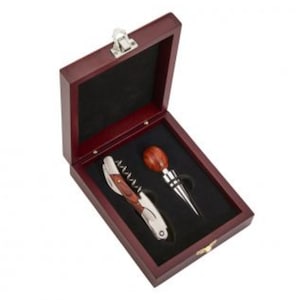 May include: A wooden box containing a wine opener and a bottle stopper. The box is made of dark wood and has a hinged lid. The wine opener is made of metal and has a wooden handle. The bottle stopper is made of wood and has a metal top.