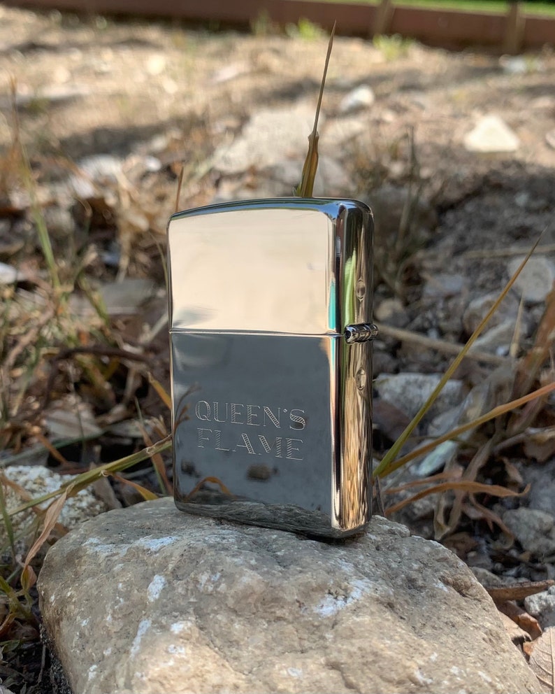 May include: A silver lighter with the words "QUEEN'S FLAME" engraved on the front.