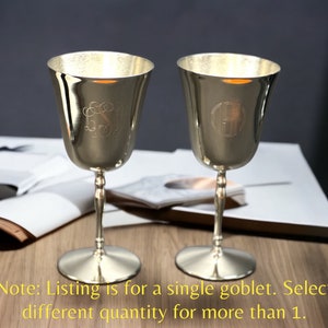 May include: Two silver goblets with engraved initials. The goblets have a flared bowl, slender stem, and a round base. The image includes text that says, "Note: Listing is for a single goblet. Select different quantity for more than 1."