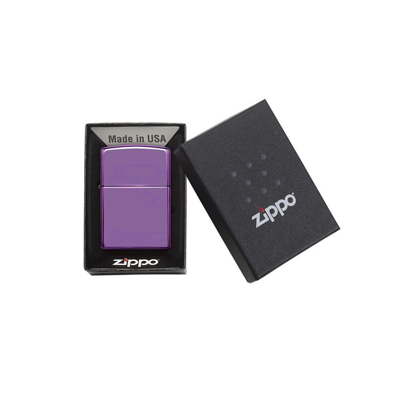 May include: A purple Zippo lighter in its original box. The box is black with the Zippo logo in white. The lighter is made in the USA.