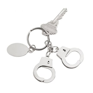 May include: Silver key chain with a key, a round tag, and two silver handcuffs.