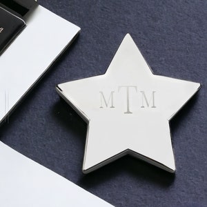 May include: A silver star-shaped paperweight with the initials "MTM" engraved on the front.