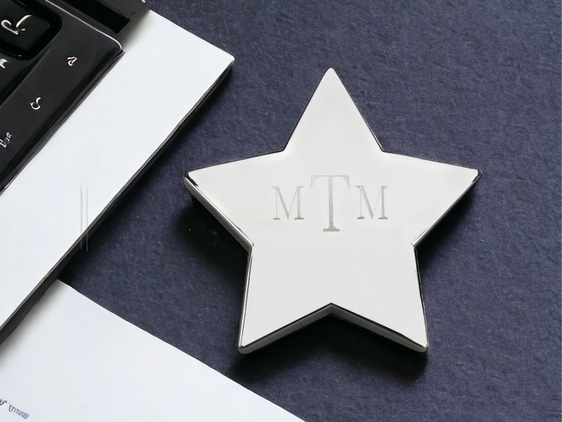 May include: A silver star-shaped paperweight with the initials "MTM" engraved on the front.