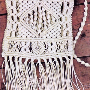 Peut inclure: Un sac en macramé blanc avec une bordure en franges. Le sac est réalisé à l'aide d'une technique de nouage et présente un motif géométrique.