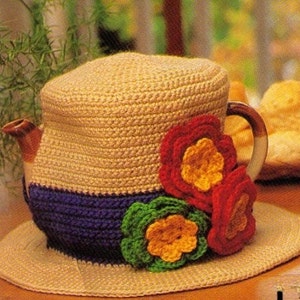 May include: A crocheted teapot cozy with a straw hat design and colorful flower accents. The cozy is made with brown, blue, green, yellow, and red yarn.