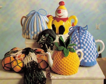 May include: A collection of knitted teapot cosies in various colours and patterns, including a blue and white checked design, a yellow and green pineapple design, a blue and white striped design, and a black and green design. The cosies are displayed on a white surface.