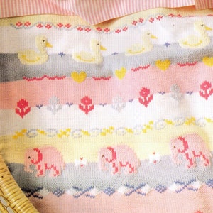 Può includere: Una copertina per neonati lavorata a maglia con un motivo a righe multicolore che presenta anatre, elefanti e fiori. La copertina è realizzata con filato morbido e ha una texture delicata.