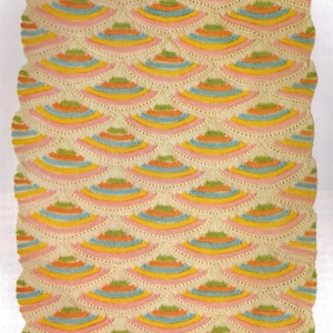 May include: A crocheted baby blanket with a scalloped edge and a repeating pattern of colorful arcs. The blanket is made with a white yarn and features pink, yellow, blue, and green accents.