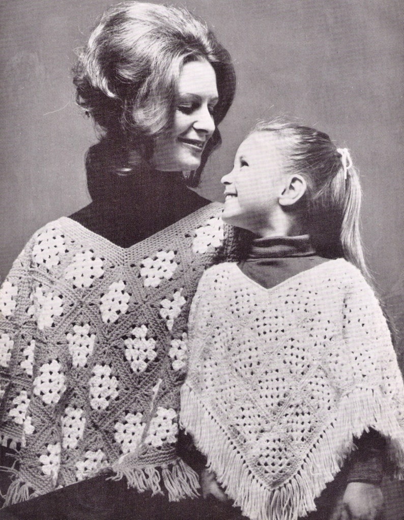 Puede incluir: Una foto en blanco y negro de dos personas que llevan ponchos de ganchillo. La mujer lleva un poncho con un patr&oacute;n blanco y gris, y la ni&ntilde;a lleva un poncho blanco con flecos.