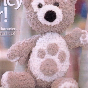 May include: A plush brown and white teddy bear with a paw print design on its chest and feet. The bear has black eyes and a black nose.