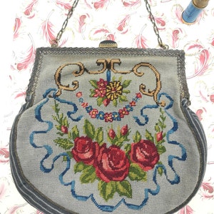 Könnte beinhalten: Eine vintage graue und blaue bestickte Handtasche mit einem Blumendesign mit Rosen und Bändern. Die Tasche hat einen silbernen Kettenriemen und einen Metallverschluss.