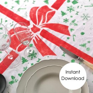 Op de afbeelding: Wit tafelkleed met een rood lint en strik. Het tafelkleed is versierd met groene kerstboompjes, sneeuwvlokken en andere feestelijke ontwerpen. De tekst "Direct downloaden" is zichtbaar in de rechterbenedenhoek van de afbeelding.