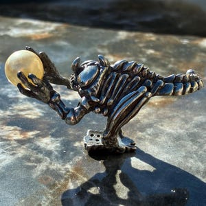 Puede incluir: Una taza de cerámica blanca con un asa negra y el texto "But First, Coffee" en negro, con una fuente de estilo manuscrito. La taza está sobre una superficie blanca.