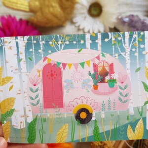 May include: A pink camper van with a white trim and a window with a view of green plants. The camper van is surrounded by green trees and bushes. The camper van has a sign that says 'Alice de Moraes'.