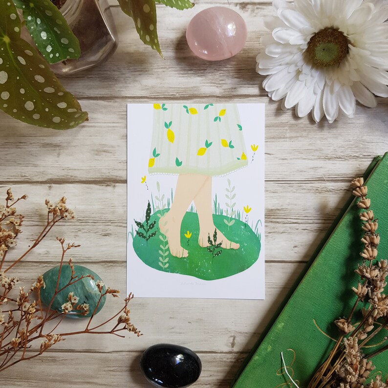 May include: A white and green illustration of a person's legs and feet walking on green grass with flowers. The person is wearing a white dress with a lemon pattern.