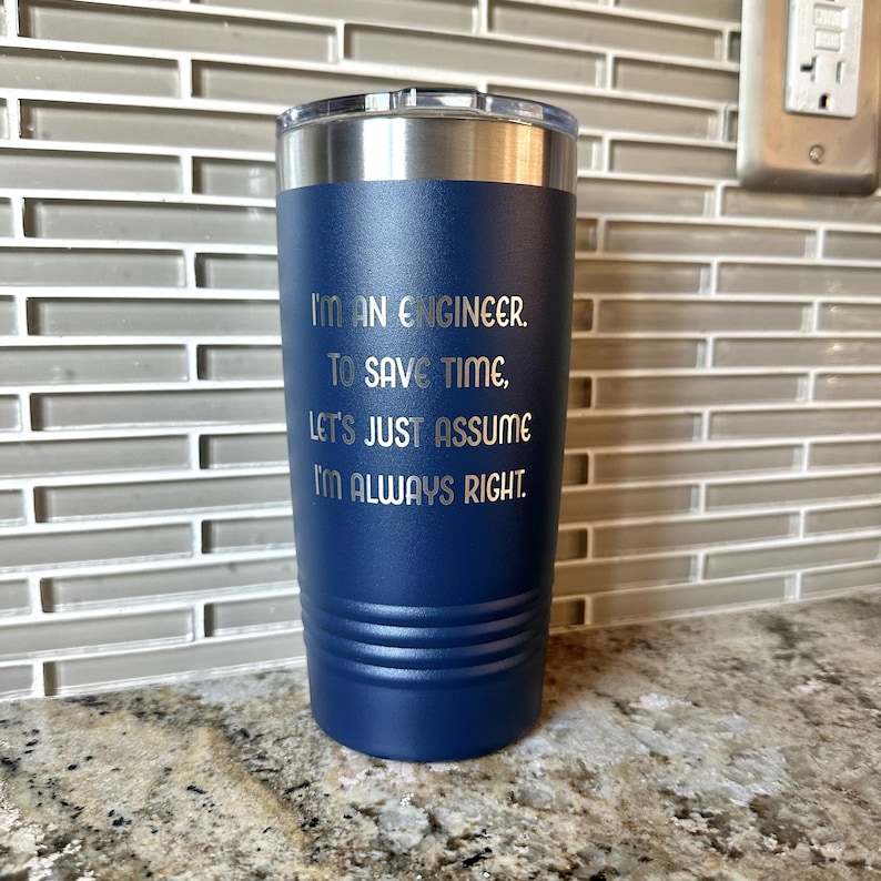 Puede incluir: Un vaso t&eacute;rmico azul marino con tapa plateada. El vaso tiene el texto "I'M AN ENGINEER. TO SAVE TIME, LET'S JUST ASSUME I'M ALWAYS RIGHT." en letras plateadas. El vaso cil&iacute;ndrico parece ser de acero inoxidable.