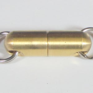 May include: A cylindrical brass magnetic clasp with two silver-colored metal rings attached to each end. The clasp is composed of two connected segments. The object is set against a white background.