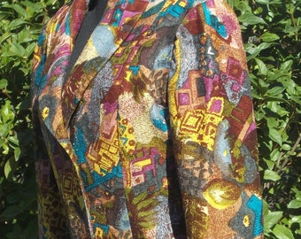May include: A blazer featuring a multi-colored abstract pattern in shades of brown, teal, yellow, and magenta. The garment has a notched lapel, long sleeves, and a single flap pocket on the side. The fabric has a textured, woven appearance.