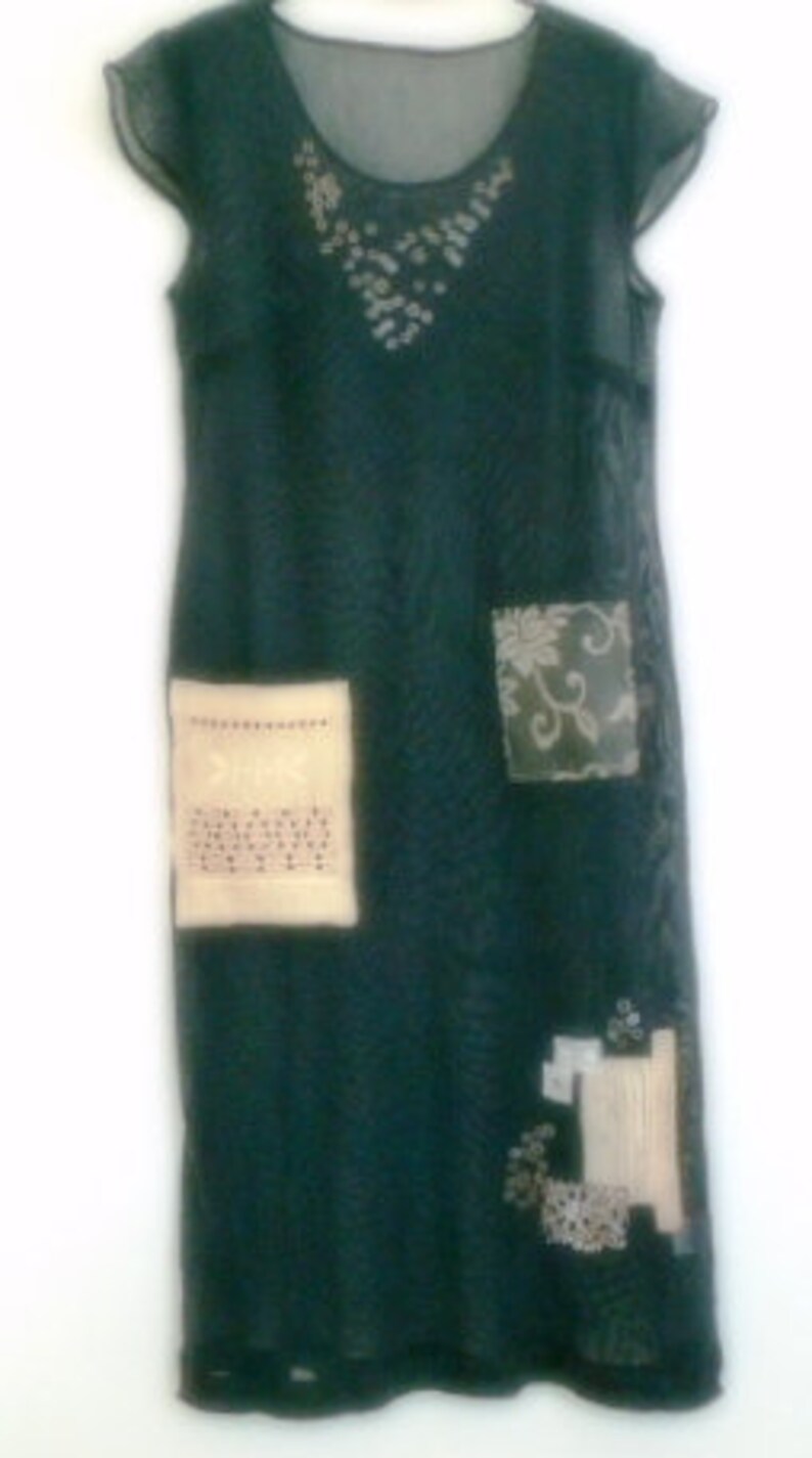 May include: A dark green, sheer, sleeveless dress with a beaded neckline and embroidered patches. The dress has a loose fit and a flowing silhouette.