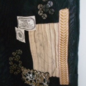 May include: A black fabric bag with a beige fabric panel and a gold trim. The bag has a label that reads "The Art Gallery, 1100, Painting, Amsterdam, Holland".