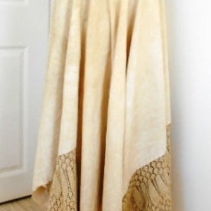 May include: A long, cream-colored skirt with a lace trim. The skirt is made of a soft, flowing fabric and has a simple, elegant design.