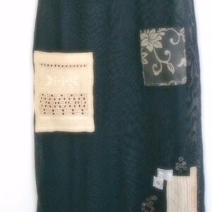 May include: A dark green skirt with a variety of fabric patches sewn on. The patches include a cream-colored square with black embroidery, a floral print fabric patch, and a beige fabric patch with a white design.