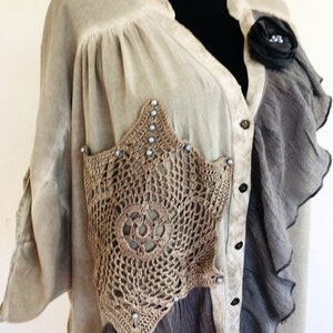 Peut inclure: Un haut crocheté beige, gris et marron avec une broche de fleur noire. Le haut a un devant boutonné et un ourlet à volants.