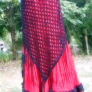 Puede incluir: Una falda de crochet roja y negra con un dobladillo con volantes. La falda est&aacute; hecha de un material delicado y de encaje y tiene una silueta fluida.