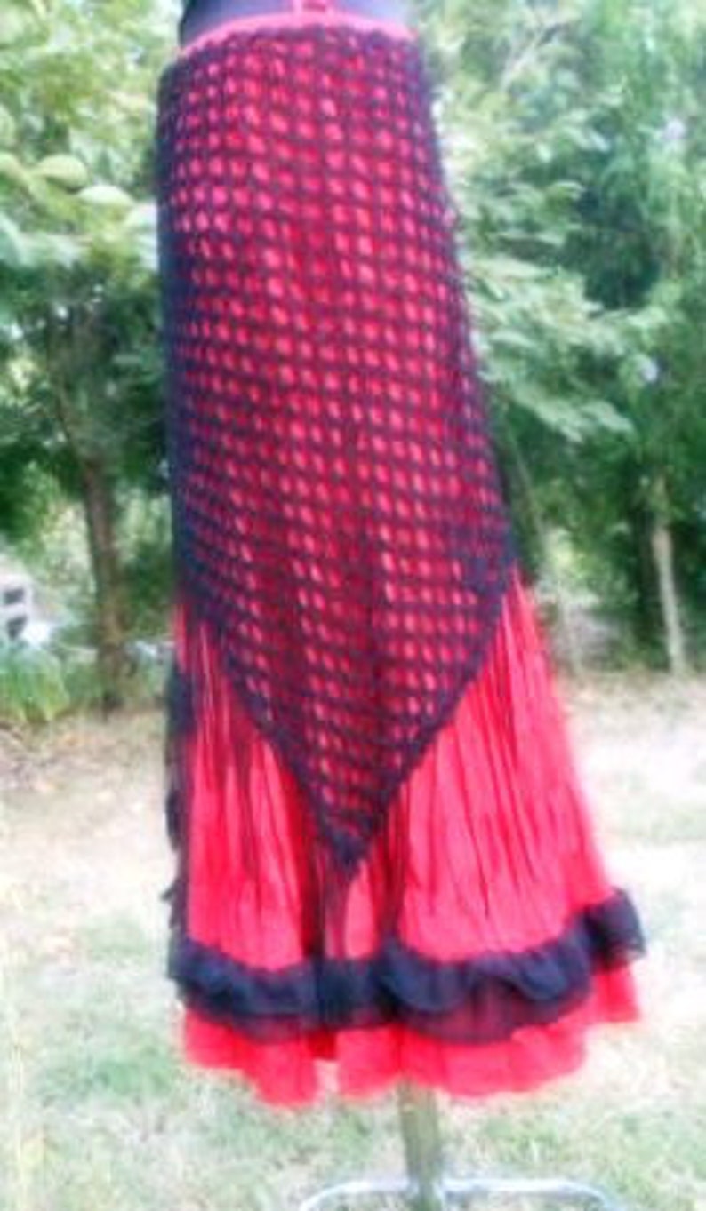 Puede incluir: Una falda de crochet roja y negra con un dobladillo con volantes. La falda est&aacute; hecha de un material delicado y de encaje y tiene una silueta fluida.