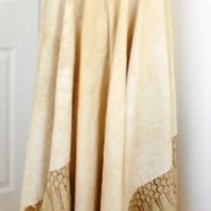 May include: A long, cream-colored skirt with a lace trim. The skirt is made of a lightweight fabric and has a flowy silhouette.