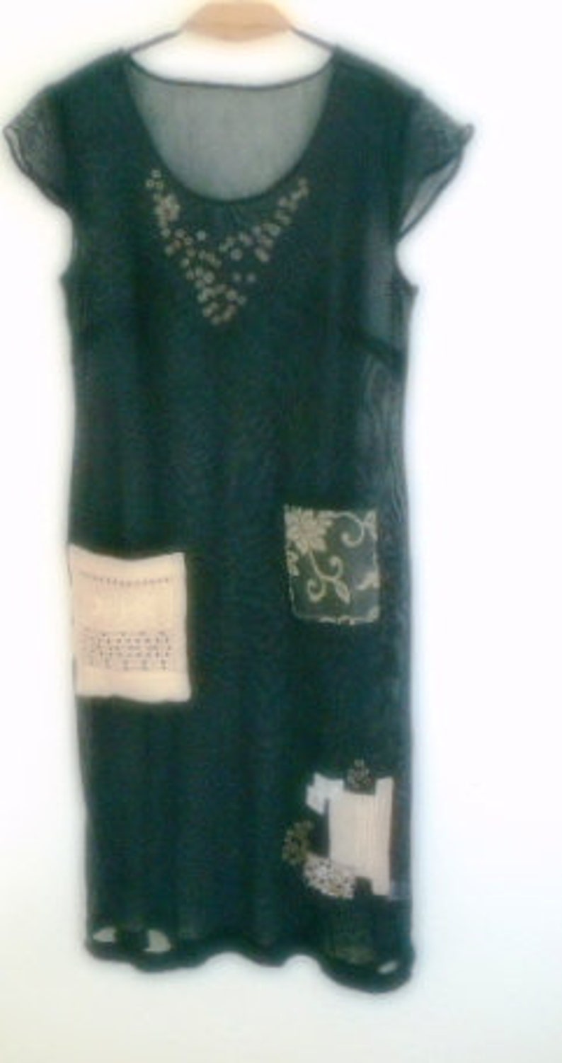 May include: A dark green, sheer, sleeveless dress with a beaded neckline and patchwork details. The dress has a loose fit and a flowing silhouette.