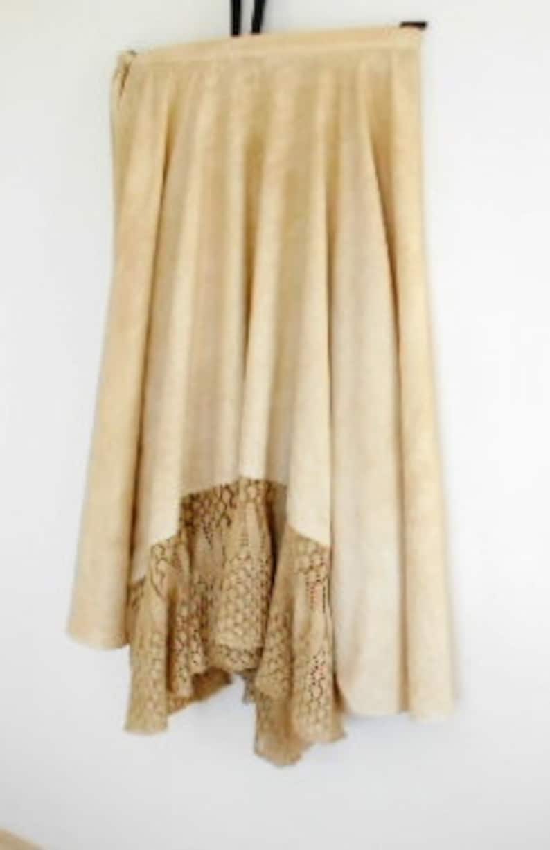 May include: A beige suede skirt with a brown crochet trim. The skirt is a-line and has a slight flare.