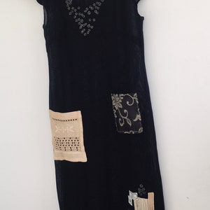 May include: A black sheer dress with a floral design and lace trim. The dress has a scoop neck and short sleeves.