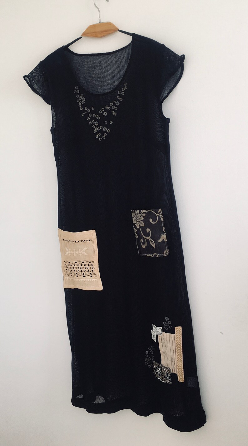 May include: A black sheer dress with a floral design and lace trim. The dress has a scoop neck and short sleeves.