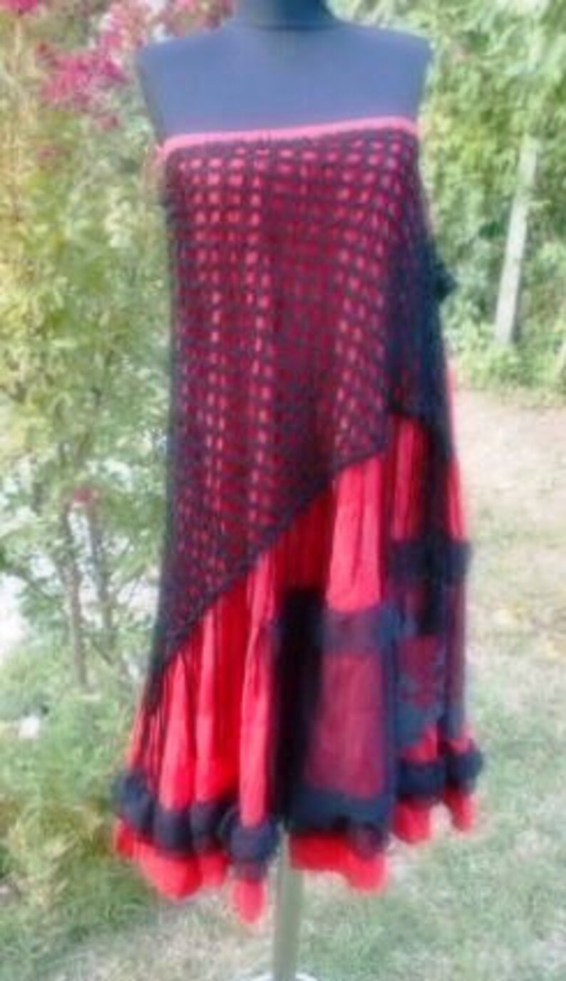 Puede incluir: Una falda roja y negra de varias capas con una superposici&oacute;n de ganchillo. La falda tiene un dobladillo con volantes y est&aacute; hecha de una tela ligera.