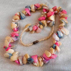 Puede incluir: Un collar de varias hebras hecho de piezas de concha rosa, blanca y azul. El collar est&aacute; enhebrado en una cadena plateada fina y tiene un cierre de broche.