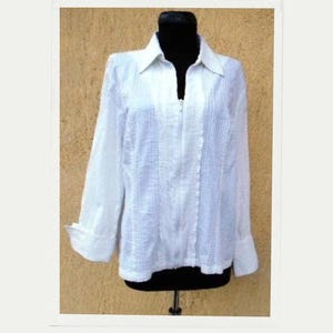 May include: White long-sleeve button-up shirt with a zipper closure. The shirt has a textured fabric and a slightly loose fit.