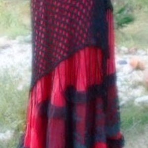 Puede incluir: Una falda roja y negra de varias capas con una superposici&oacute;n de crochet negro. La falda tiene un dobladillo con volantes y est&aacute; hecha de una tela ligera.
