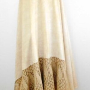 May include: A long, cream-colored skirt with a lace trim. The skirt is made of a soft, flowing fabric and has a wrap-around style.