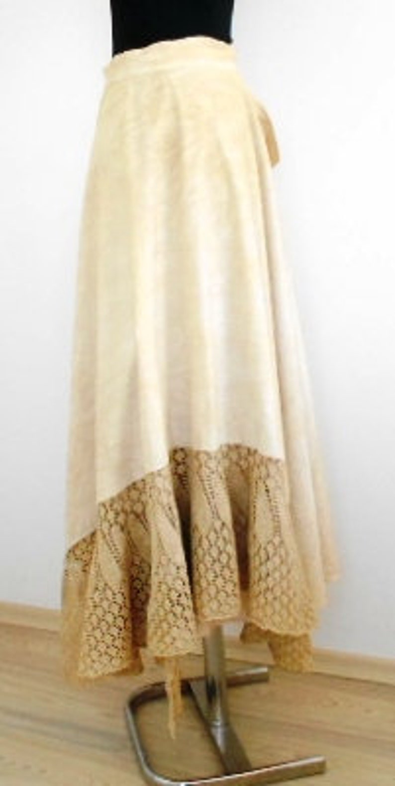 May include: A long, cream-colored skirt with a lace trim. The skirt is made of a soft, flowing fabric and has a wrap-around style.