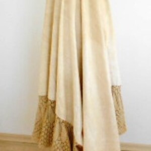 May include: A white suede skirt with a brown patterned trim. The skirt is full and flowing, and it has a high waist.