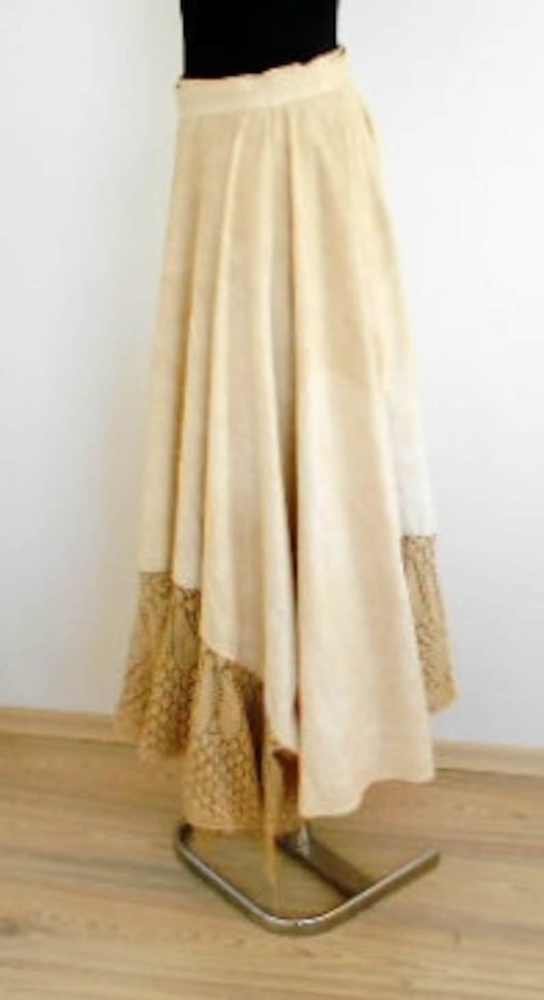 May include: A white suede skirt with a brown patterned trim. The skirt is full and flowing, and it has a high waist.
