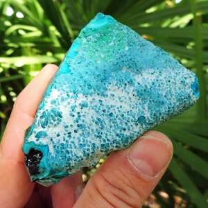 May include: A blue and white, rough-textured, irregularly shaped piece of turquoise gemstone. The turquoise has a speckled pattern of white and blue.