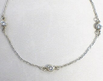 May include: A delicate silver chain bracelet with three small, clear gemstones.