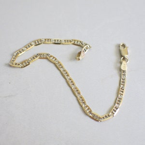May include: A gold chain bracelet with a mariner link design and small clear stones set into the links. The bracelet has a lobster claw clasp.