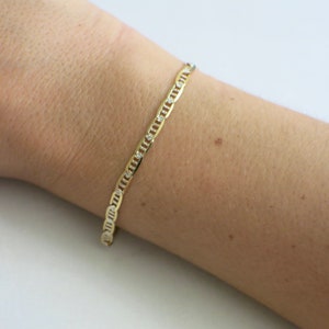 May include: A gold chain bracelet with small clear stones set into the links.