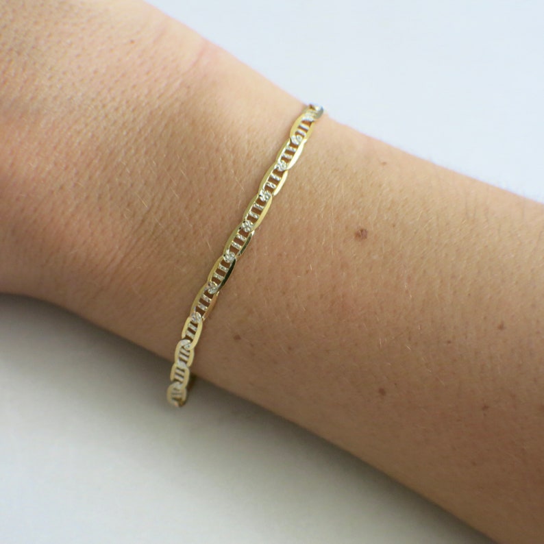 May include: A gold chain bracelet with small clear stones set into the links.