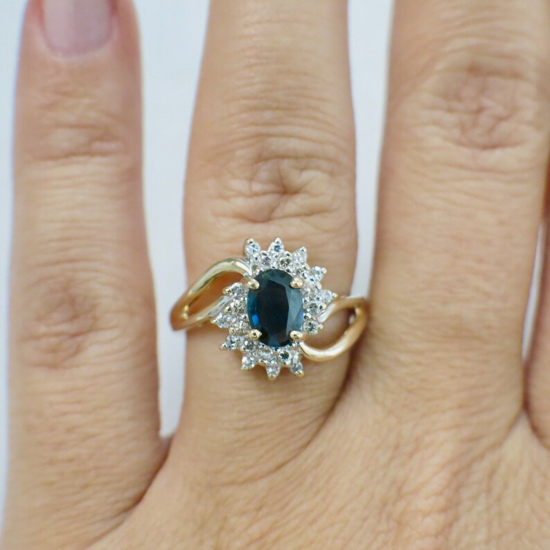 May include: A gold ring with a blue oval gemstone surrounded by smaller white gemstones.