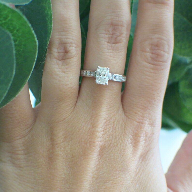 May include: A silver ring with a square-shaped diamond in the center and smaller diamonds set in the band.