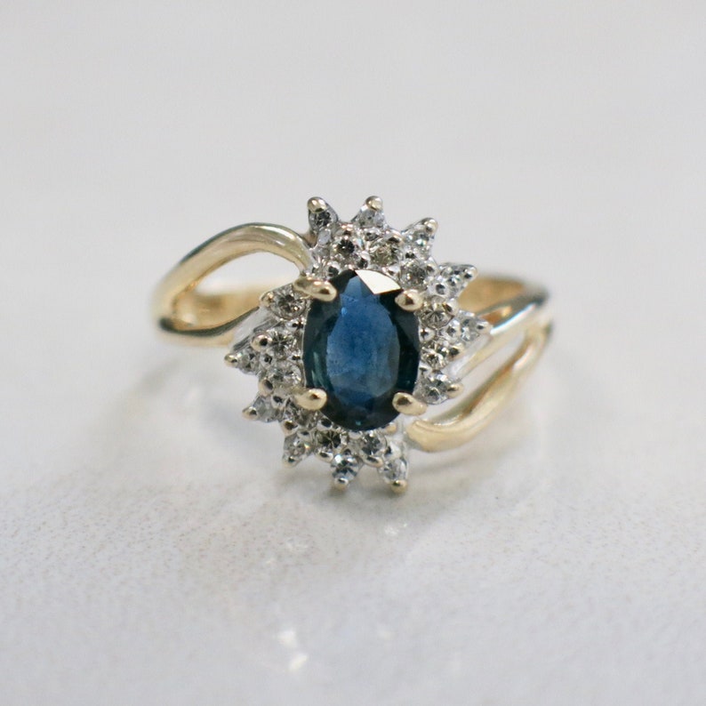 May include: A gold ring with a large blue sapphire surrounded by smaller diamonds.